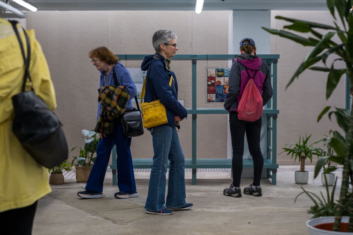 group of people at an art exhibition, looking at art surrounded by plants