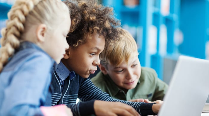 Three children are engaged with a compute in the classroom