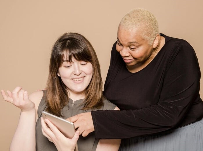 Two women scrolling through the screen of an iPad